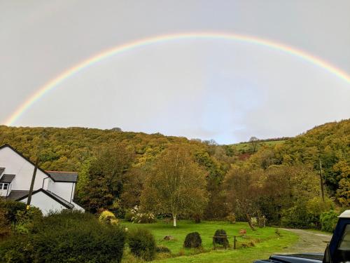 a rainbow over a house and a field with cows at Millslade Country House in Lynton
