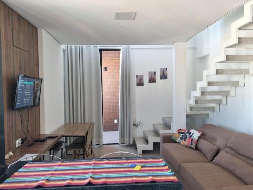 a living room with a couch and a staircase at Apartamento luxo no centro in Ubá