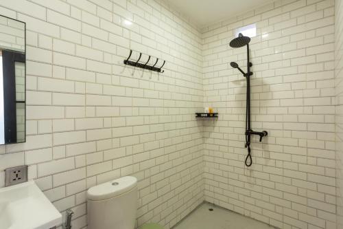 a white tiled bathroom with a shower and a toilet at Alam Nirwana in Gretek