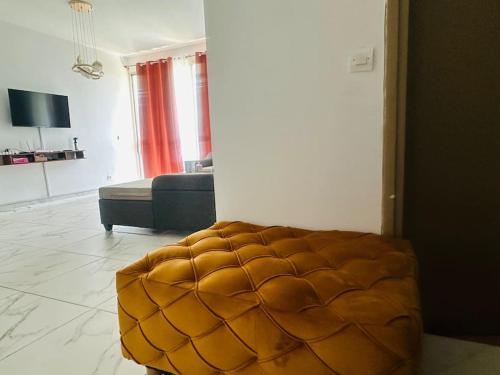 ein Wohnzimmer mit einem braunen, gesteppten Ottoman in der Unterkunft Résidence du bonheur in Abidjan