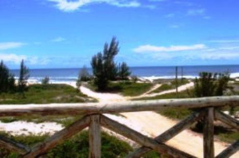 a dirt road leading to a beach with the ocean at Pousada Pé na Areia in Garopaba