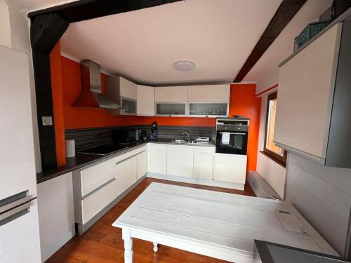 - une cuisine avec des placards blancs et un mur orange dans l'établissement Alsace Mountain House, à Munster
