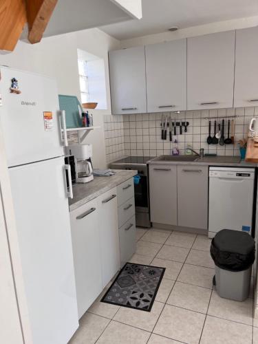 une cuisine avec des armoires blanches et un réfrigérateur blanc dans l'établissement Maison avec grande terrasse à 100m de la plage, à La Tranche-sur-Mer