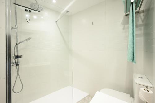 a white bathroom with a shower and a toilet at Cautivo 2 in Estepona