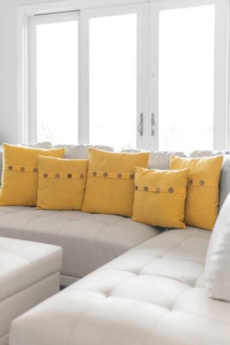 a white couch with yellow pillows in a living room at Sunrise in Paradise-BeachFront-Fenced Yard-Pets-Sleeps 11 in Galveston