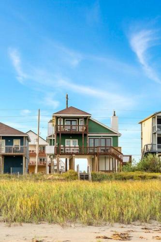 a large house sitting on the beach near the sand at Sunrise in Paradise-BeachFront-Fenced Yard-Pets-Sleeps 11 in Galveston