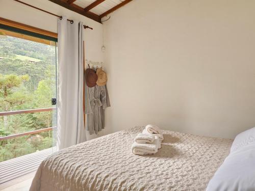 a bedroom with a bed with towels on it at Chalé LuNê Vista para a Montanha , Banheira Imersão Externa e Lareira in Gonçalves