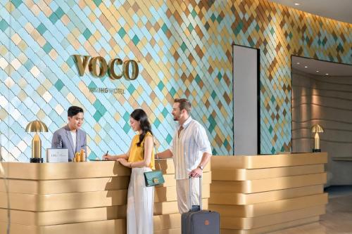 a group of three people standing at a counter in a store at voco Ma Belle Danang by IHG in Da Nang