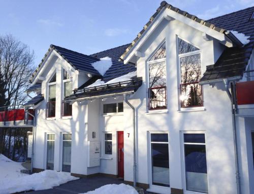 a white house with a red door in the snow at Viadukt in Willingen