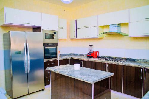 a kitchen with a stainless steel refrigerator and wooden cabinets at Dej's Luxury Apartment House 1 in Lekki