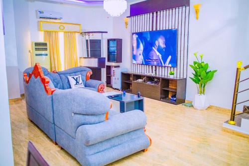 a living room with a blue couch and a tv at Dej's Luxury Apartment House 1 in Lekki
