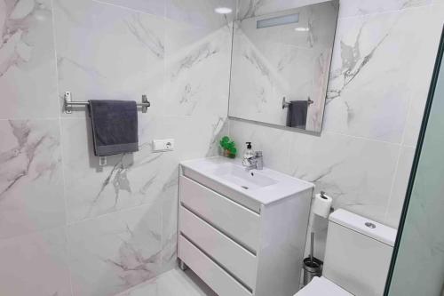 a white bathroom with a sink and a mirror at Club Paraiso in Adeje