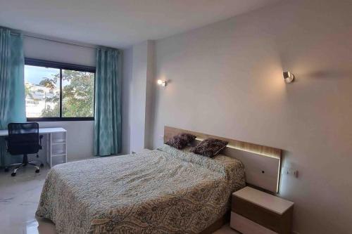 a bedroom with a bed and a desk and a window at Club Paraiso in Adeje