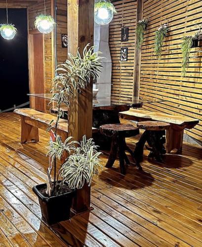 a room with tables and potted plants on a wooden floor at Sítio vale das pedras in Barracão