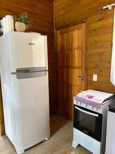 a white refrigerator in a kitchen with a stove at Sítio vale das pedras in Barracão