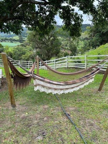 a hammock sitting in the grass next to a fence at Sítio vale das pedras in Barracão