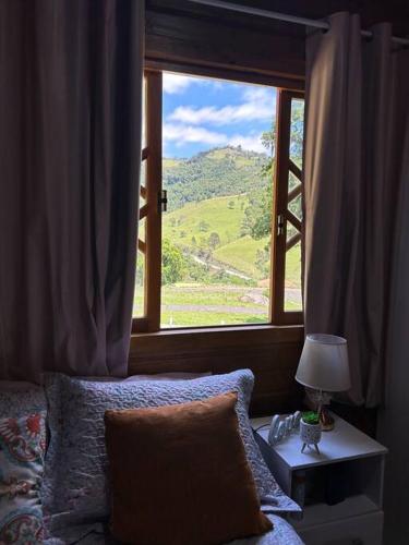 a bedroom with a window with a view of a mountain at Sítio vale das pedras in Barracão