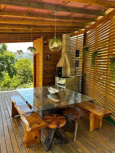 a glass table and bench on a wooden deck at Sítio vale das pedras in Barracão