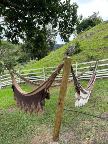 a hammock attached to a fence in a field at Sítio vale das pedras in Barracão