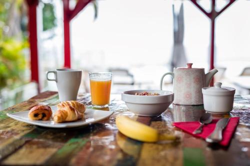 a table with a breakfast of croissants and orange juice at Le Rayon Vert - Hôtel & Restaurant VUE SUR MER in Deshaies