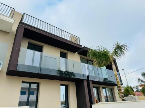 a building with a balcony and a palm tree at Déco ArtRooms in Porto Cesareo