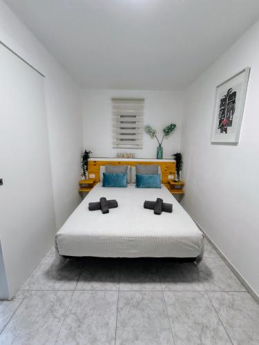 a white bedroom with a large bed with blue pillows at Apartamento OCEAN PEARL in Corralejo