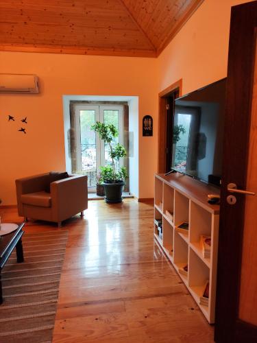 a living room with orange walls and a television at Casa de Campo Vale do Ceira in Góis