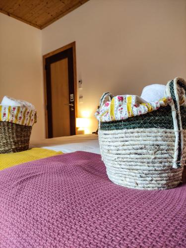 two baskets sitting on a bed with a purple rug at Casa de Campo Vale do Ceira in Góis