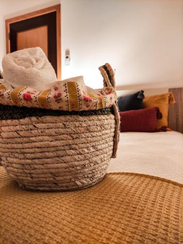 a basket filled with pillows on top of a bed at Casa de Campo Vale do Ceira in Góis