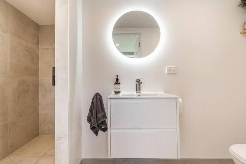 a white bathroom with a sink and a mirror at The Black Barn - 2 Bedrooms in Kumeu