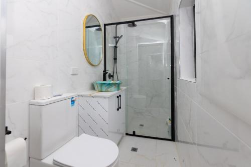 a white bathroom with a toilet and a shower at Glenelg Modern Studio, QBed,Wifi in Glenelg
