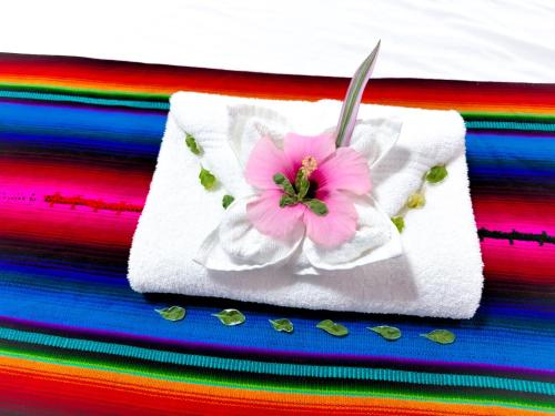 a white towel with a pink flower on it at Caribbean Shores Belize in Hopkins