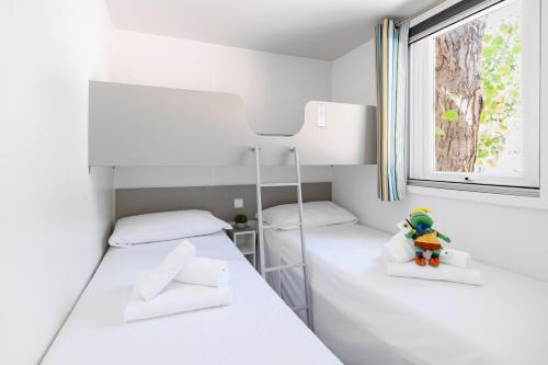 two beds in a small room with a window at Club del Sole Romagna Family Resort in Riccione