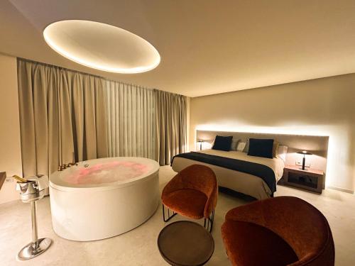 a hotel room with a tub and a bed at Olea Suites in Alcalá del Júcar