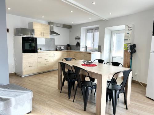 une cuisine avec une table en bois et des chaises noires dans l'établissement La Source du Bonheur-Clim Parking Wifi - CLG Savoie, à Saint-Pierre-dʼAlbigny