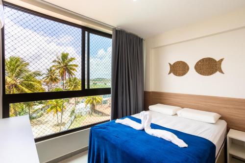 ein Schlafzimmer mit einem Bett und einem großen Fenster in der Unterkunft Capri Residence in Porto De Galinhas
