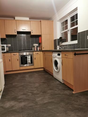 a kitchen with wooden cabinets and a washer and dryer at Sun Gardens Retreat- can sleep 10 with 4 Double Beds & 2 sofa beds in Stockton-on-Tees