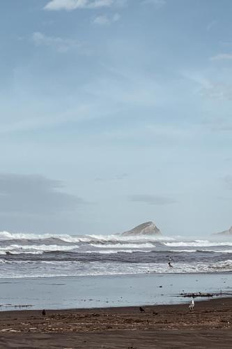 a beach with waves in the ocean and a group of people at Estudio 33 in San Juan de la Arena