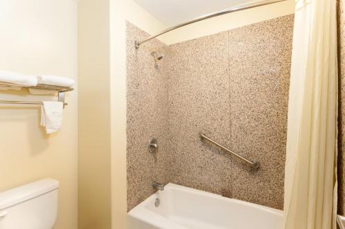a bathroom with a shower with a toilet and a sink at Travelodge by Wyndham Brea in Brea