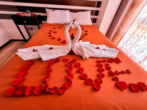 two swans made out of red rose petals on a bed at Pukantu Hostal in Puno