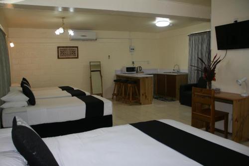 a hotel room with three beds and a kitchen at Moatoga Hotel in Apia