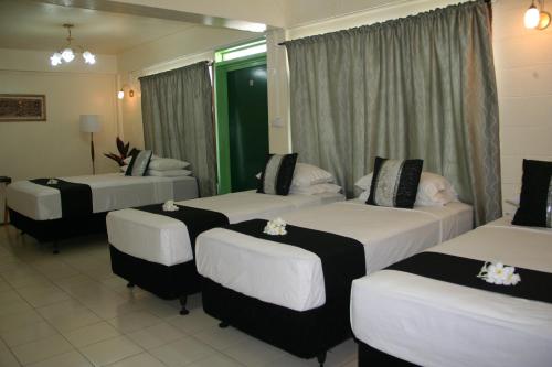 a hotel room with four beds with flowers on them at Moatoga Hotel in Apia