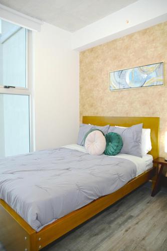 a bedroom with a bed with two pillows on it at Grotto at 28, City Views and Wonderland Vibes! in Hatillo
