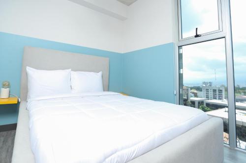 a white bed in a room with a large window at Sunflower at 12, City Views and Wonderland Vibes! in Hatillo