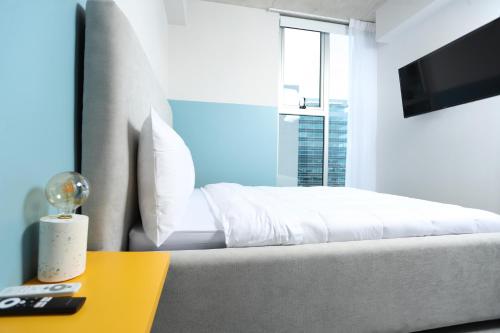 ein Schlafzimmer mit einem weißen Bett und einem gelben Tisch in der Unterkunft Sunflower at 12, City Views and Wonderland Vibes! in Hatillo