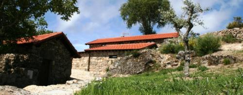 a building with a red roof in a field at Abrigo de Montanha in Montalegre