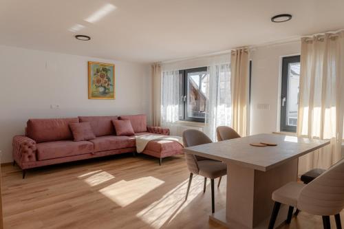 a living room with a red couch and a table at Hiša S'TJE Ljubljana Airport in Cerklje na Gorenjskem
