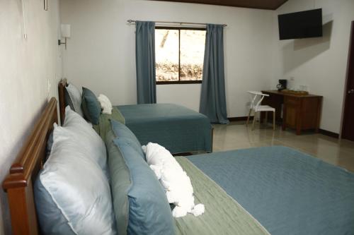 a bedroom with two beds with pillows and a television at Cañon de la Vieja Lodge in Liberia