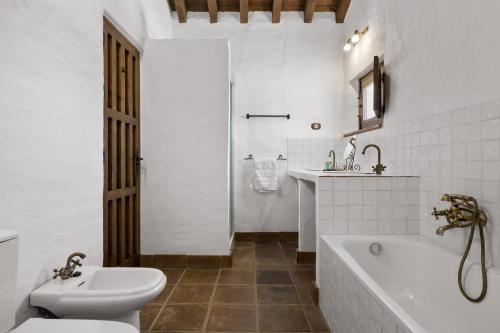 een badkamer met een bad, een toilet en een wastafel bij Hacienda Riogordo in Ríogordo