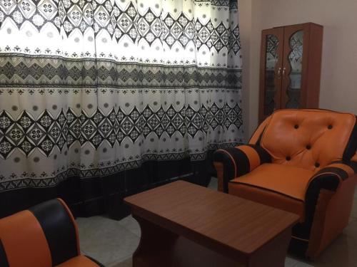 a room with a chair and a table and a curtain at Mary Apartments in Mbale
